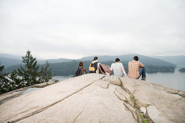 Gente en la roca junto a un lago - foto de stock
