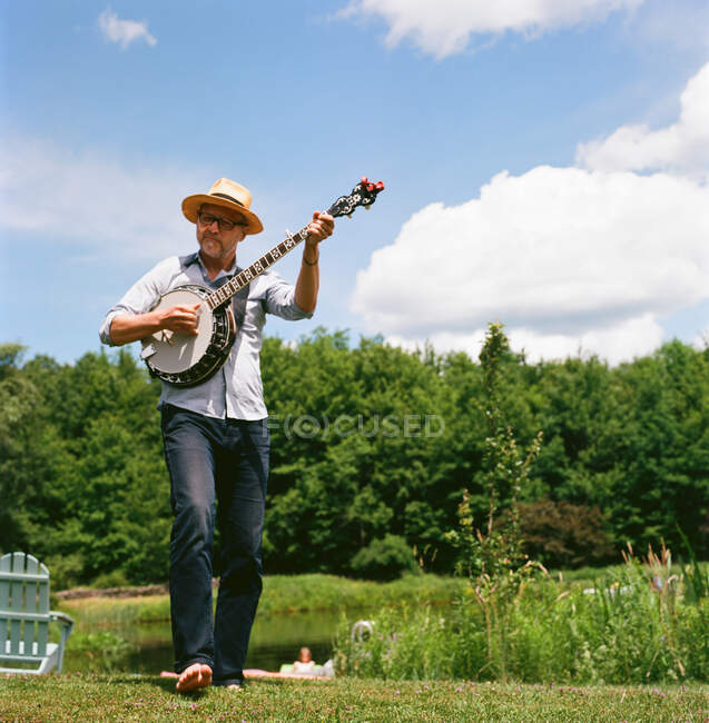 Mature man outdoors playing banjo — Stock Photo