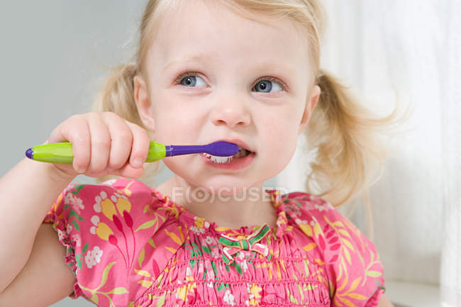 Niñita cepillándose los dientes - foto de stock