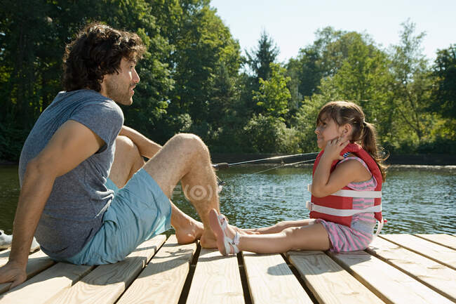 Padre e hija en embarcadero en el lago - foto de stock