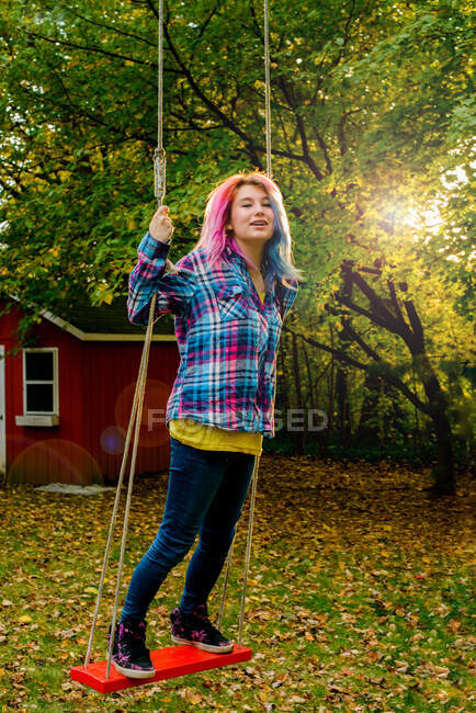 Портрет дівчини-підлітка з багатокольоровим волоссям, на садовому гойдалці — стокове фото