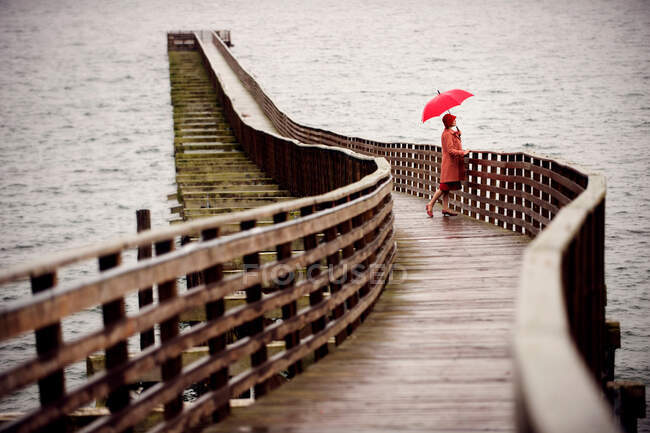 Donna con ombrello su pontile di legno — Foto stock