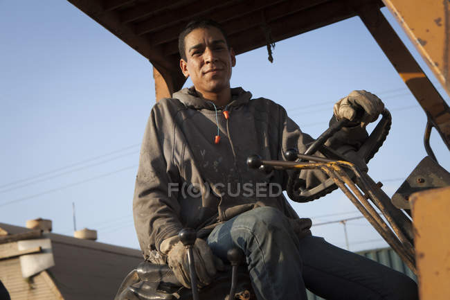 Man on construction site sitting on heavy machinery — Stock Photo