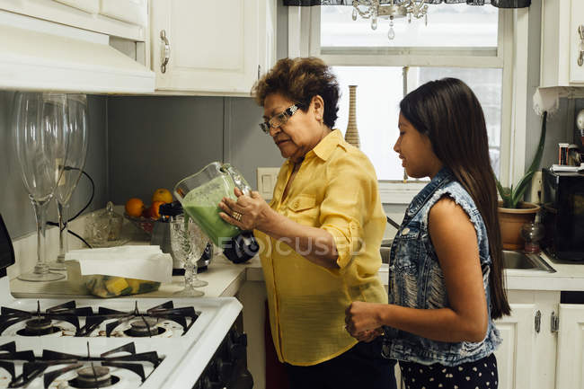 Grandmother and granddaughter preparing smoothies — Stock Photo