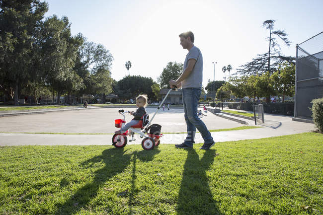 Padre spingendo giovane figlio sul triciclo — Foto stock