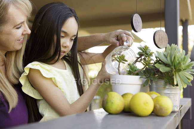 Mother and daughter watering houseplant — Stock Photo