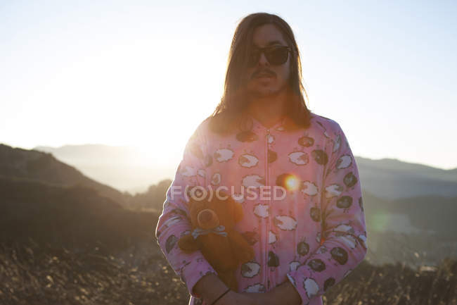 Retrato de un hombre con pijama rosa, sosteniendo un oso de peluche, Malibu Canyon, California, EE.UU. - foto de stock