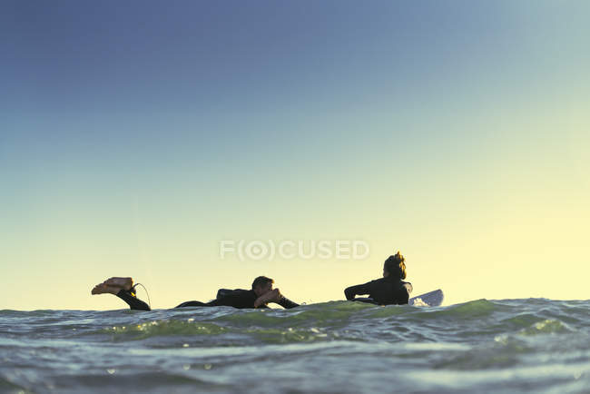 Surfing couple paddling surfboards at sea, Newport Beach, California, USA — Stock Photo