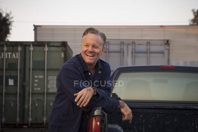 Hombre apoyado en camión y sonriendo - foto de stock