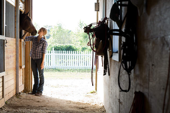 Mid adult woman with horse in stable — Stock Photo