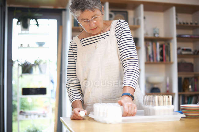 Старша жінка на кухні, роблячи косметику — стокове фото