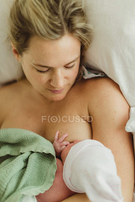 Overhead view of adult woman breast feeding newborn baby daughter in bed — Stock Photo