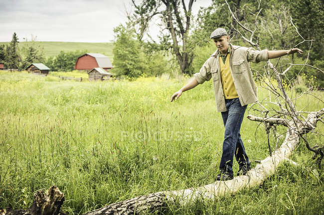 Young man arms open walking on fallen tree — Stock Photo