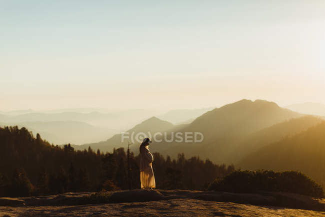 Pregnant woman in mountains touching stomach, Sequoia national park, California, USA — Stock Photo