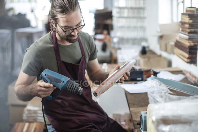 Mann erhitzt Plastikfolie auf Holzspindel in Fabrik — Stockfoto