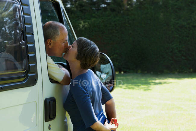 Pareja besándose fuera campervan - foto de stock