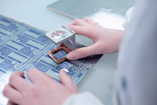 Manos de trabajadora inspeccionando circuito flexible en fábrica de electrónica flexible - foto de stock