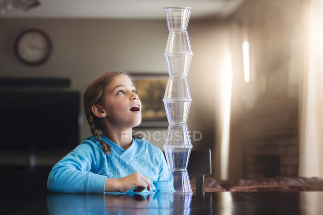 Menina olhando com espanto para copos de plástico equilibrados — Fotografia de Stock