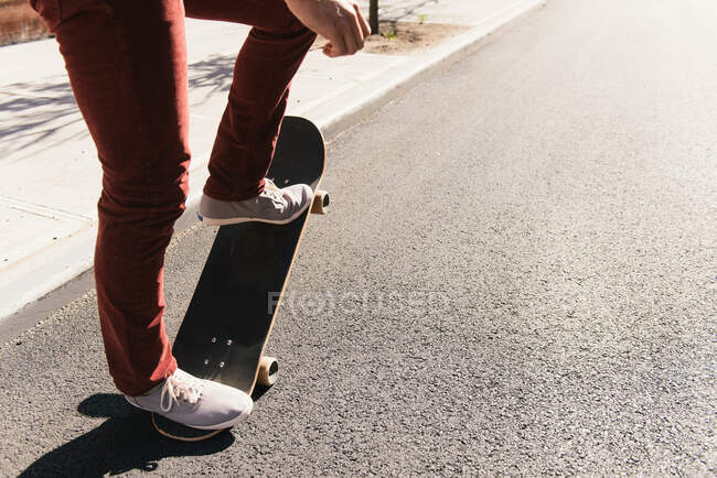 Piernas y pies de skateboarder masculino haciendo truco de skate en la carretera - foto de stock