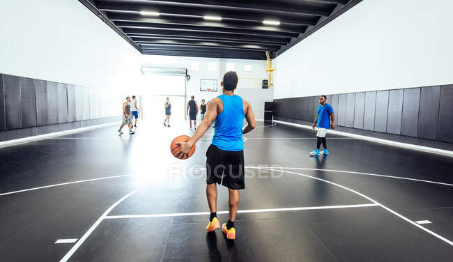 Rear view of male basketball player standing with ball at basketball practice — Stock Photo