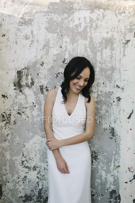 Bride leaning against wall, smiling — Stock Photo