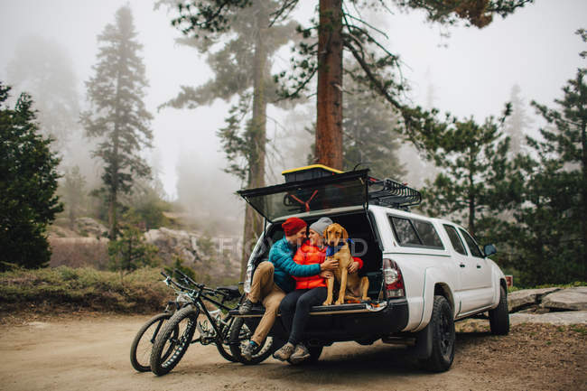 Couple and dog sitting on tailgate of jeep wagon, Sequoia National Park, California, USA — Stock Photo