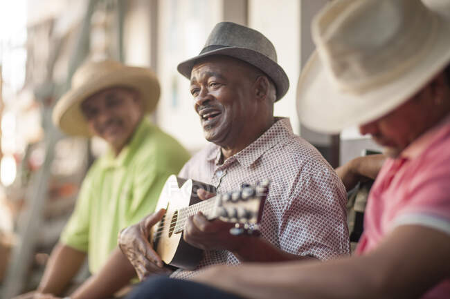 Cape Town, South Africa, three men sitting together and one playing a guitar — Stock Photo