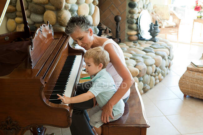 Бабушка и внук играют на пианино — стоковое фото