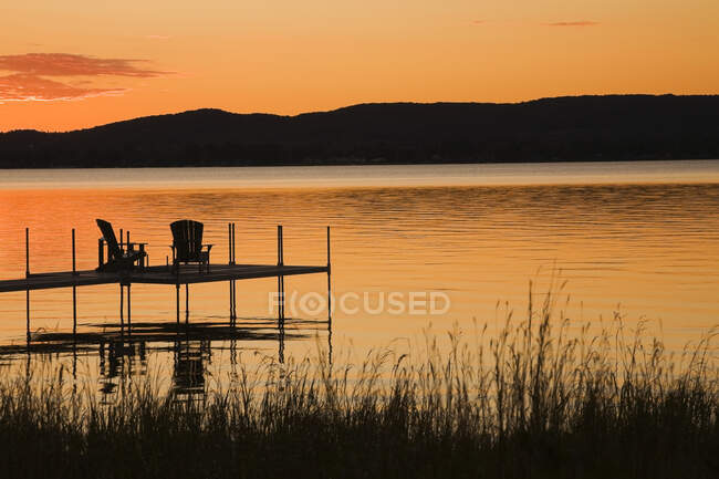 Liegeplatz mit Stühlen, am See, bei Sonnenuntergang im Sommer, Quebec, Kanada — Stockfoto