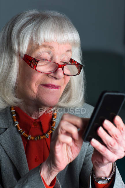 Старшая женщина с помощью смартфона — стоковое фото