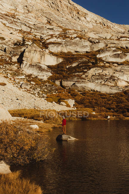 Senderista masculino mirando desde la roca del lago, Mineral King, Parque Nacional Sequoia, California, EE.UU. - foto de stock