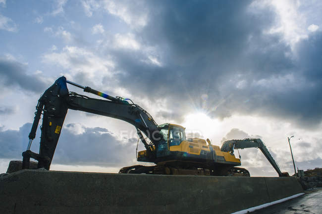 Low angle silhouetted view of two excavators parked back to back — Stock Photo