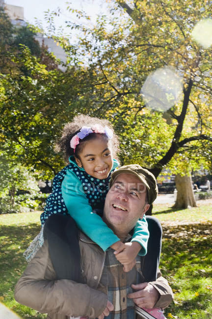 Father giving smiling daughter piggy back — Stock Photo