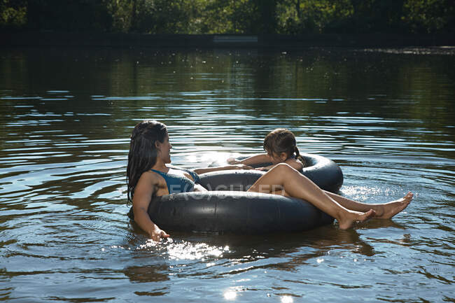 Madre e hija en el lago en anillos inflables - foto de stock