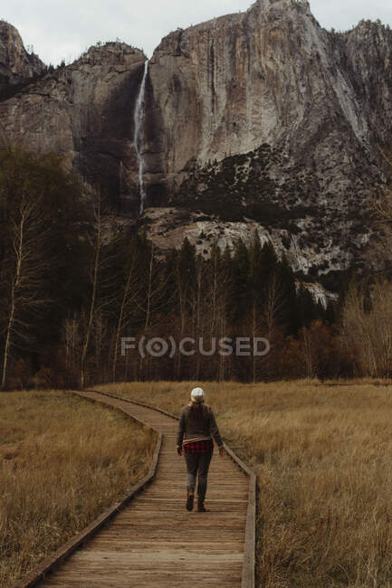 Rückansicht einer Wanderin auf der Uferpromenade in Richtung Berge, Yosemite National Park, Kalifornien, USA — Stockfoto