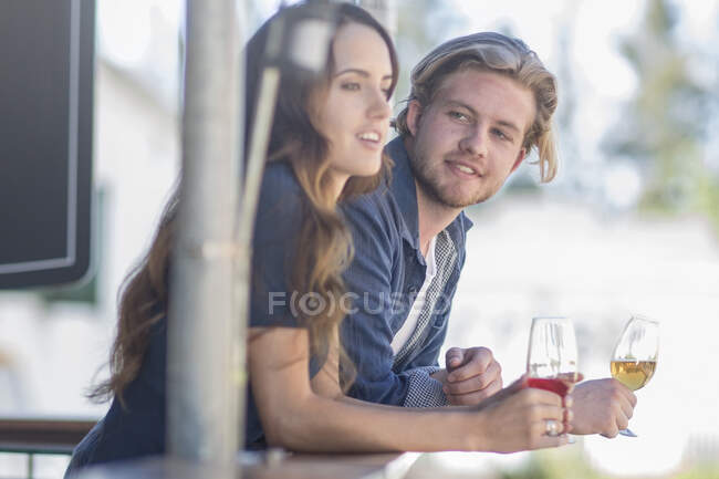 Cape Town, South Africa, young male and female conversating with one another while leaning over with beer glasses in their hands — Stock Photo