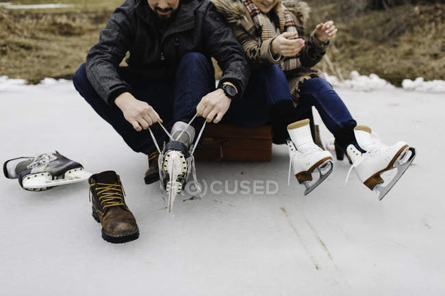 Uomo allacciatura lacci da scarpe su pattini da ghiaccio — Foto stock