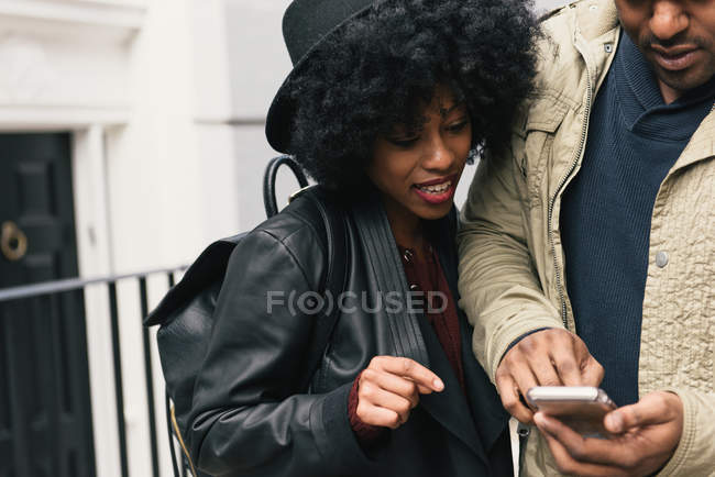 Пара на улице смотрит на смартфон — стоковое фото