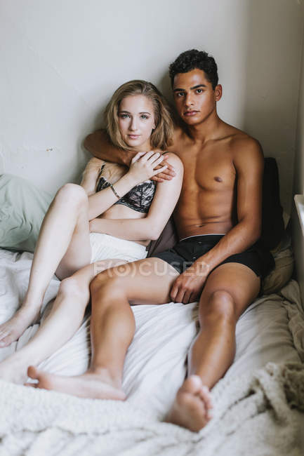 Coppia che indossa biancheria intima, seduta sul letto — Foto stock