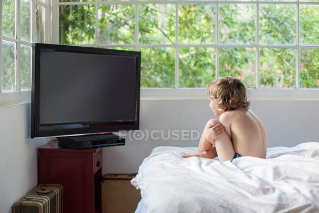 Boy watching television on bed — Stock Photo