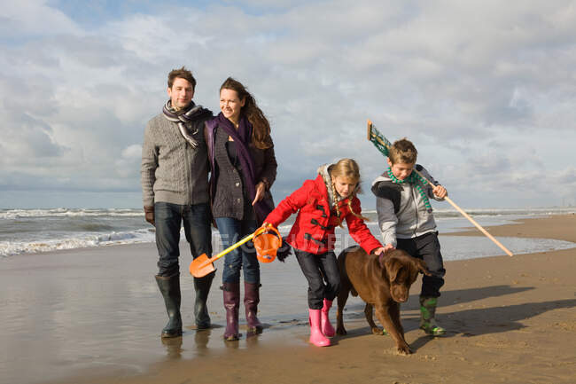 Сім'я і собака біля моря — стокове фото