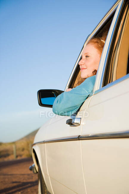 Uma jovem que se inclina pela janela de um carro — Fotografia de Stock