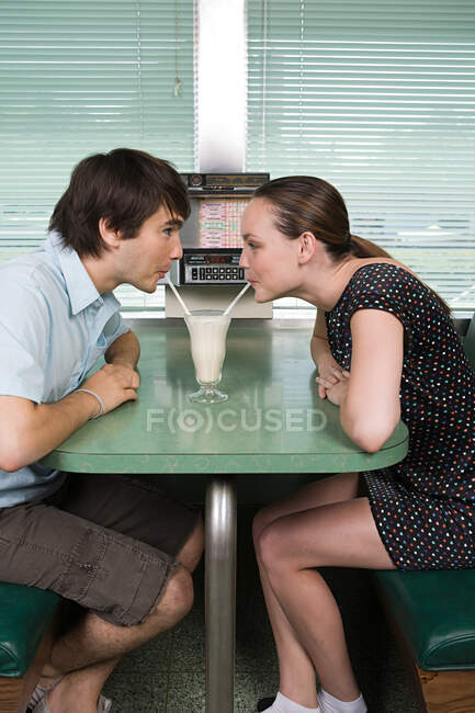 Jeune couple boire un milkshake — Photo de stock