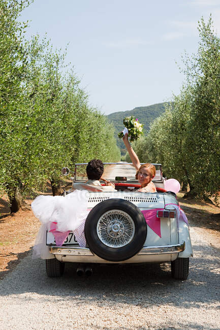 Jeunes mariés en voiture classique — Photo de stock