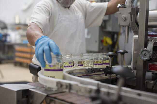 Homem manuseando frascos de vidro na linha de produção — Fotografia de Stock