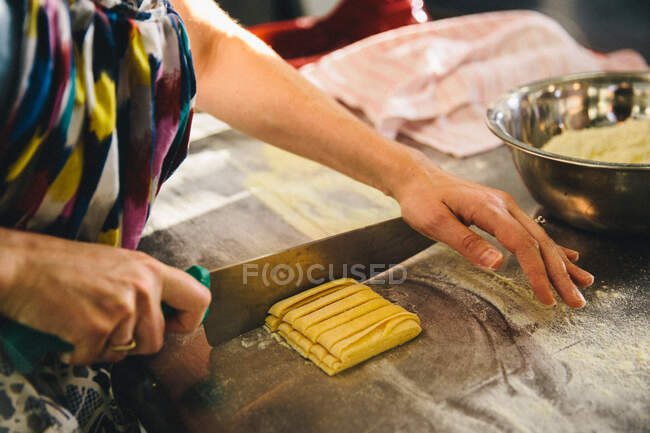 Woman cutting pasta dough with knife — Stock Photo