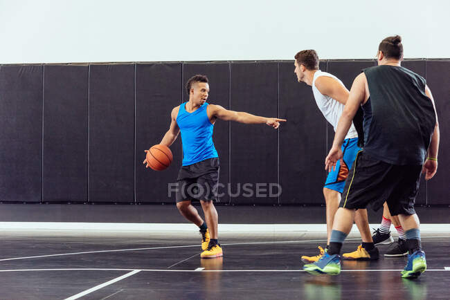 Баскетболист держит мяч и указывает на тренировку по баскетболу — стоковое фото