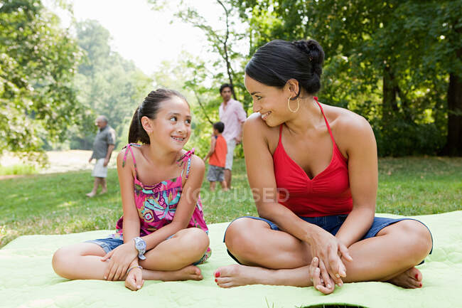 Madre e hija en manta de picnic en el parque - foto de stock