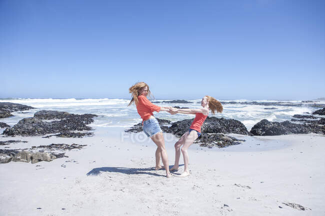 Ciudad del Cabo, Sudáfrica, dos chicas jóvenes balanceándose en la playa - foto de stock