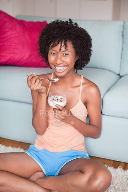 Jovem mulher comendo deserto enquanto relaxa em casa — Fotografia de Stock